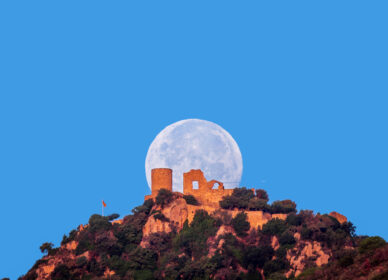 Puesta luna llena sobre castillo Burriac